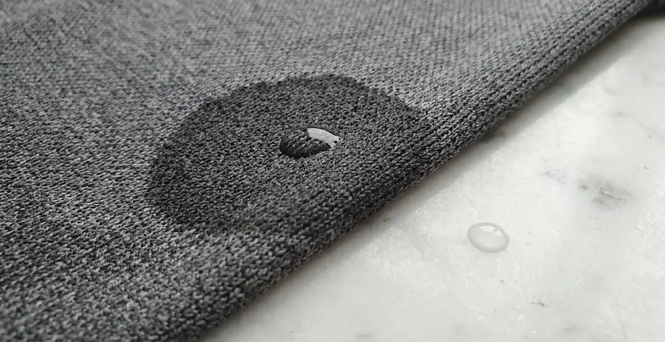 Gros plan macro sur textile technique rafraîchissant montrant les fibres super absorbantes gorgées d'eau, structure capillaire visible, diffusion latérale du liquide dans le tissu